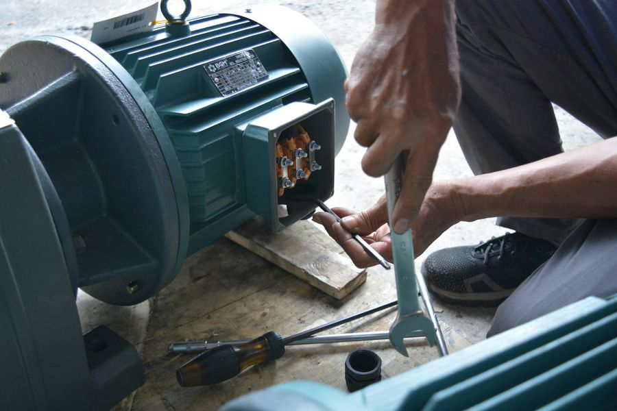 A technician's hands wiring the terminal of an electric motor